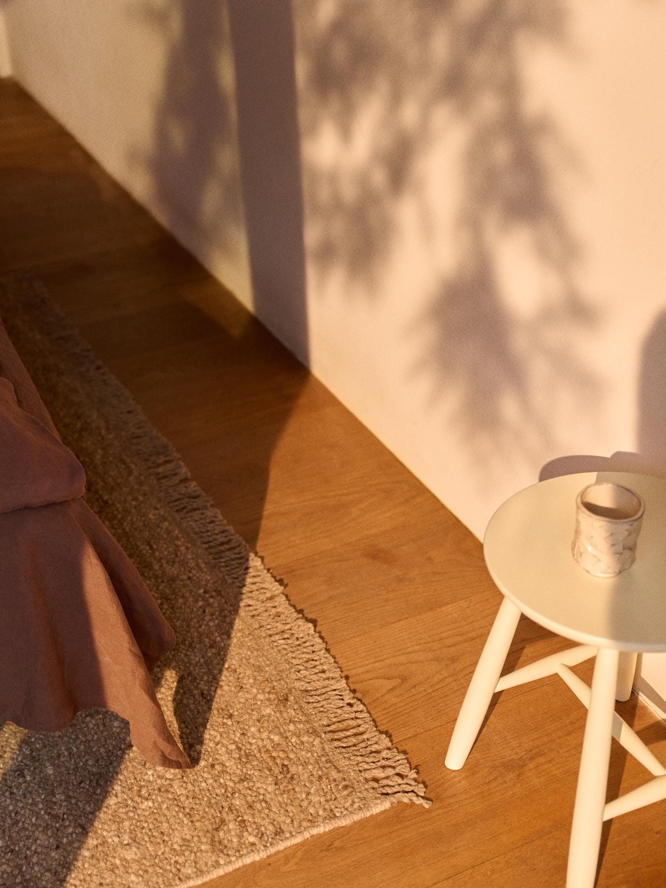 pall och beige ullmatta vid fotändan på en säng